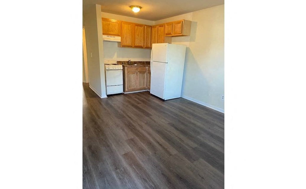a kitchen with a white refrigerator and wooden floors