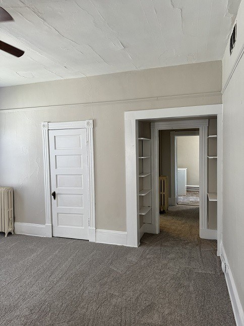 A room with a white door and a carpeted floor.