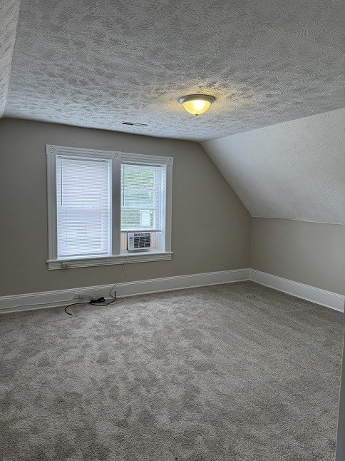 A room with a window and a carpeted floor.
