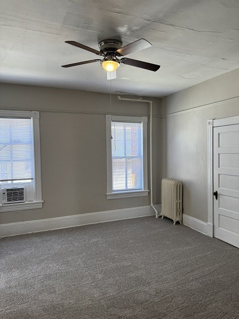 A room with a ceiling fan and a radiator on the floor.