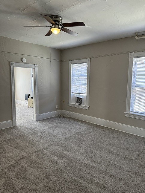 A room with a ceiling fan and carpeted floor.
