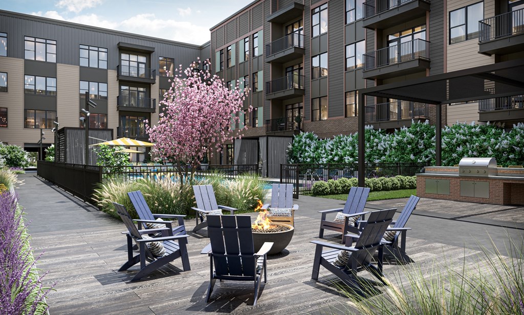 a patio with chairs and a fire pit in front of an apartment building