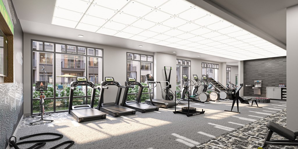 a gym with cardio equipment and large windows in a building