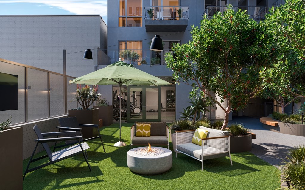 a courtyard with chairs and an umbrella and a fire pit