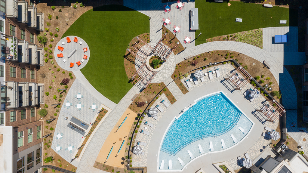 Beautiful drone shot of courtyard with pool, grills, and firepit at Link Apartments® Linden in Chapel Hill