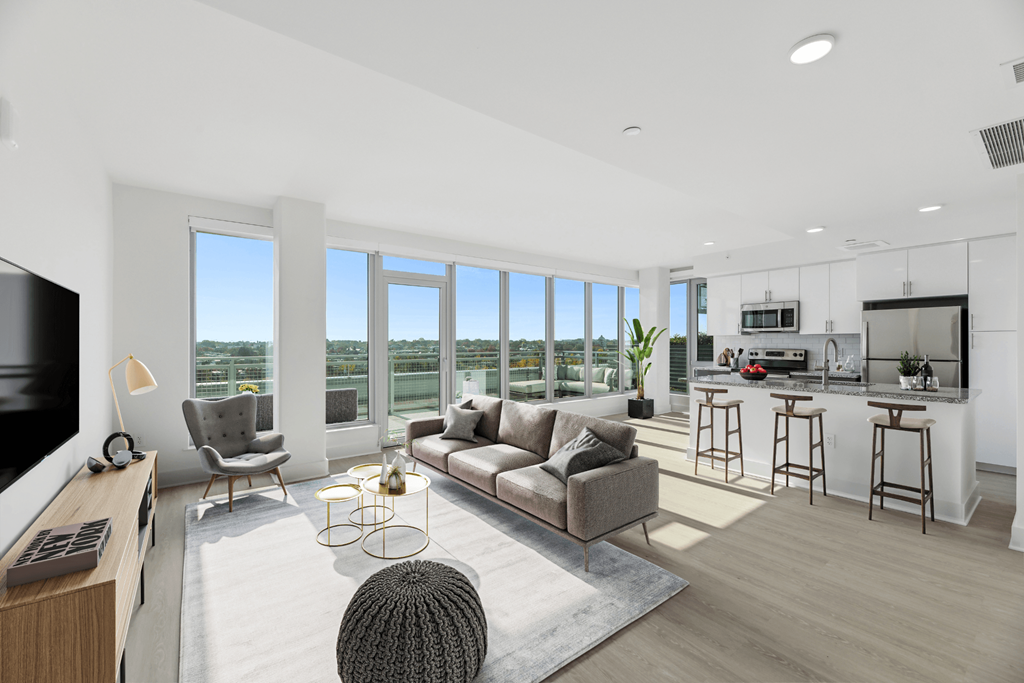 an open living room with a couch and a chair and a kitchen with a counter  at Link Apartments® H Street, Washington