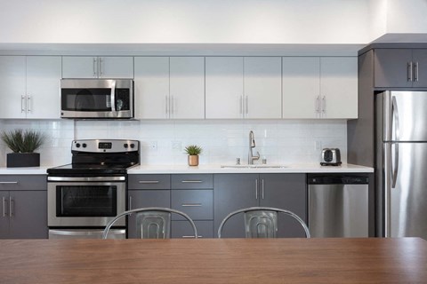 A modern kitchen with a wooden table in front.