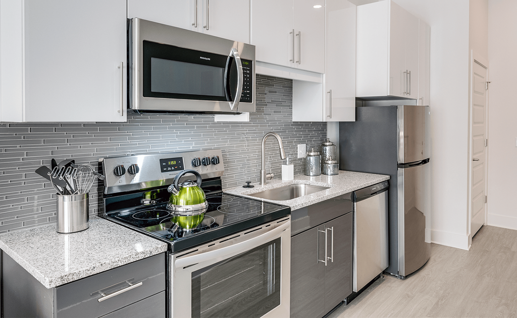 a kitchen with stainless steel appliances and white cabinets  at Link Apartments® Mixson, South Carolina