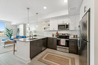 an open kitchen with stainless steel appliances and a marble counter top