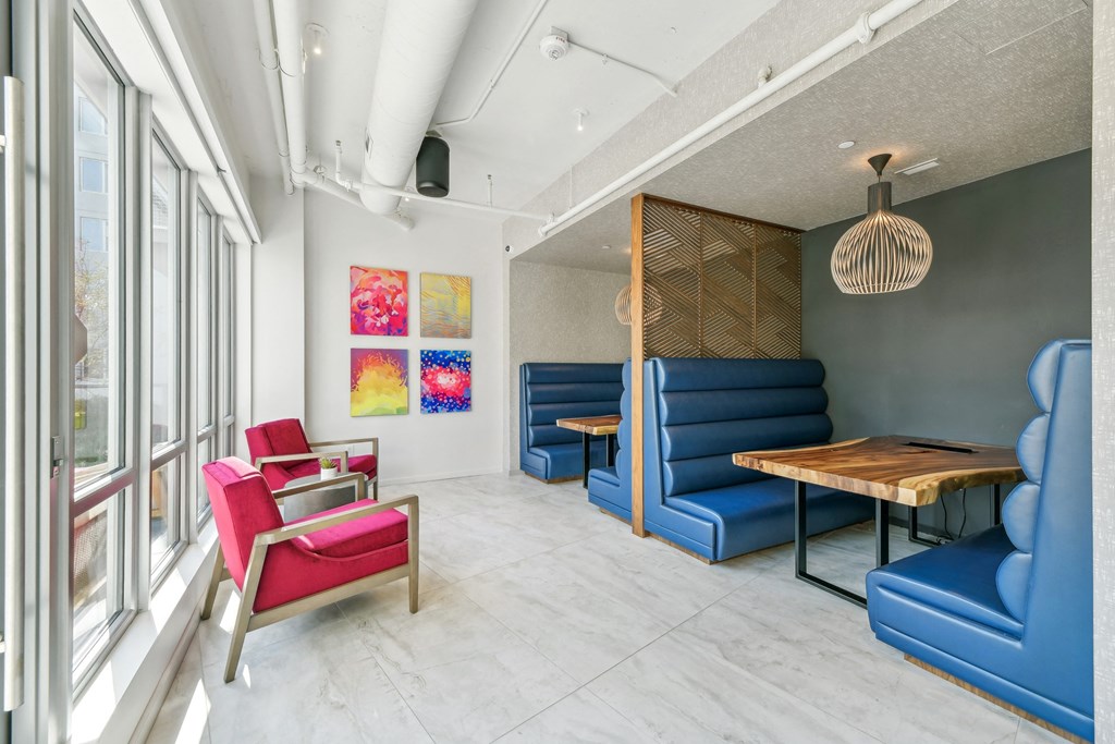 a living room with blue couches and chairs and a wooden table at Link Apartments® H Street, Washington, Washington