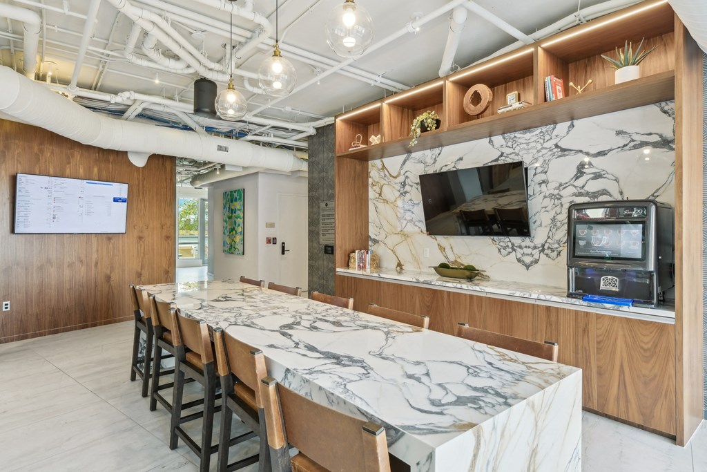 a long marble table with chairs in a room with a tv at Link Apartments® H Street, Washington, 20002