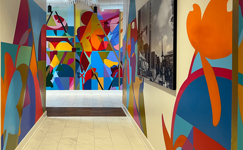 a hallway with a colorful mural on the wall and a staircase at Link Apartments® 4th Street, Winston-Salem, North Carolina