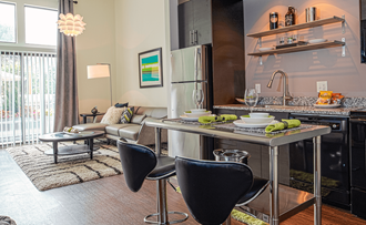 a kitchen with an island and two chairs in front of it  at Link Apartments® Canvas, Atlanta, GA, 30312 - Photo Gallery 5