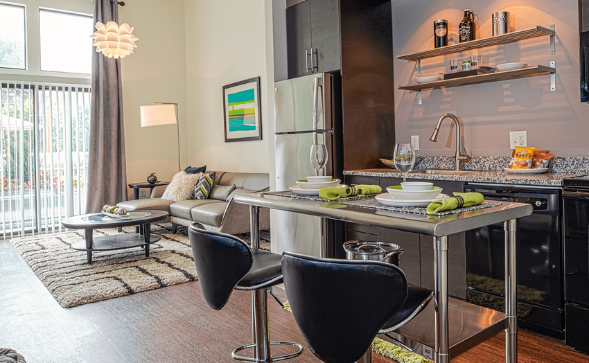 a kitchen with an island and two chairs in front of it a kitchen with an island and two chairs in front of it at Link Apartments® Canvas, Atlanta, GA, 30312 - Photo Gallery