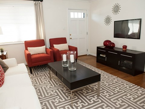 A living room with a black coffee table and red chairs.