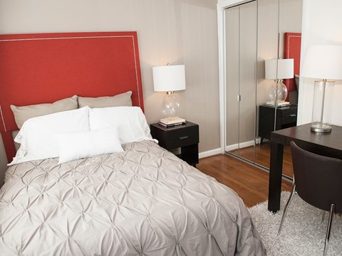 A bedroom with a large bed and a red headboard.