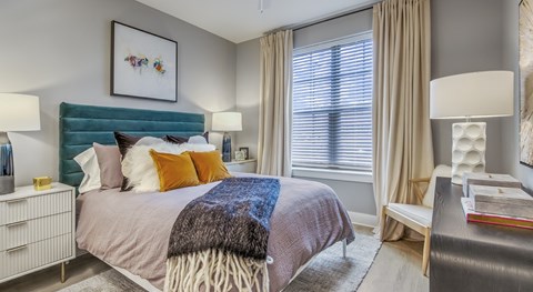 Bedroom with teal headboard and modern decor at Lumeo at Tryon Park Apartments, Charlotte, NC