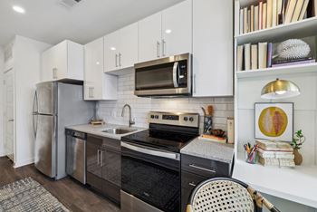 a kitchen with stainless steel appliances and white cabinets at Link Apartments® Broad Ave, Tennessee