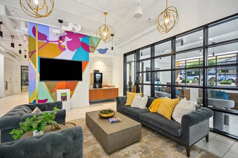 a living room with couches and a tv in a building with glass doors at Link Apartments® 4th Street, North Carolina