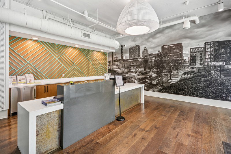 a lobby with a reception desk and a black and white photo of a city skyline at Link Apartments Innovation Quarter, Winston Salem