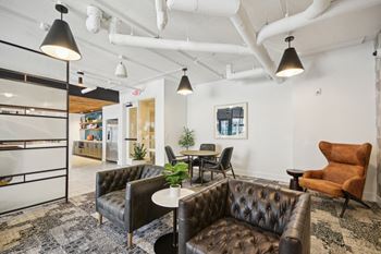 A room with a brown leather couch and a white table. at Link Apartments® 4th Street, Winston-Salem, North Carolina