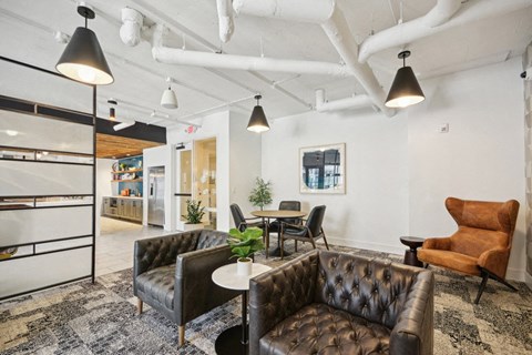 a living room with leather couches and chairs and a kitchen at Link Apartments® 4th Street, Winston-Salem, NC, 27101