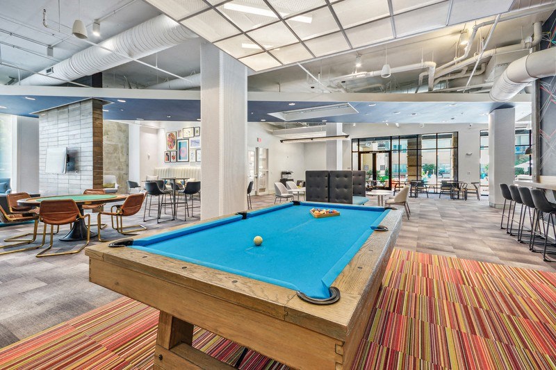 a pool table in a lobby with tables and chairs at Link Apartments Innovation Quarter, Winston Salem, NC