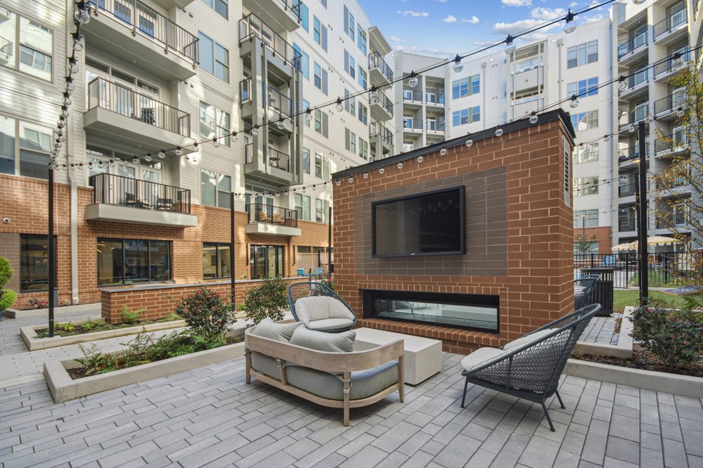 an outdoor patio with a fireplace and a couch and a chair at Link Apartments® Calyx, Chapel Hill, 27517