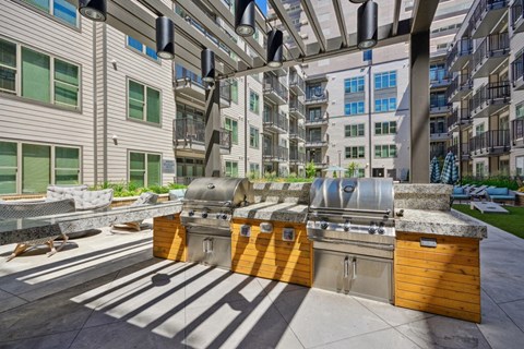 spacious clubhouse with grilling stations and apartments in the background at Link Apartments® 4th Street, Winston-Salem, 27101