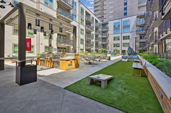 A modern outdoor seating area with a grassy lawn and concrete flooring. at Link Apartments® 4th Street, Winston-Salem, North Carolina