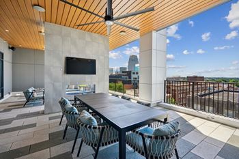 A patio with a table and chairs and a TV on the wall at Link Apartments® 4th Street, Winston-Salem, North Carolina