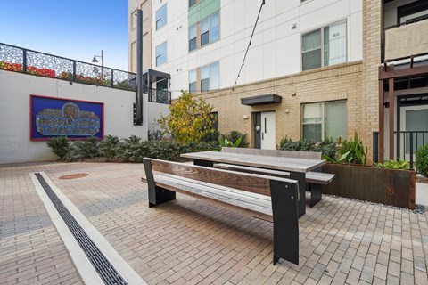 A bench is situated on a brick patio in front of a building.