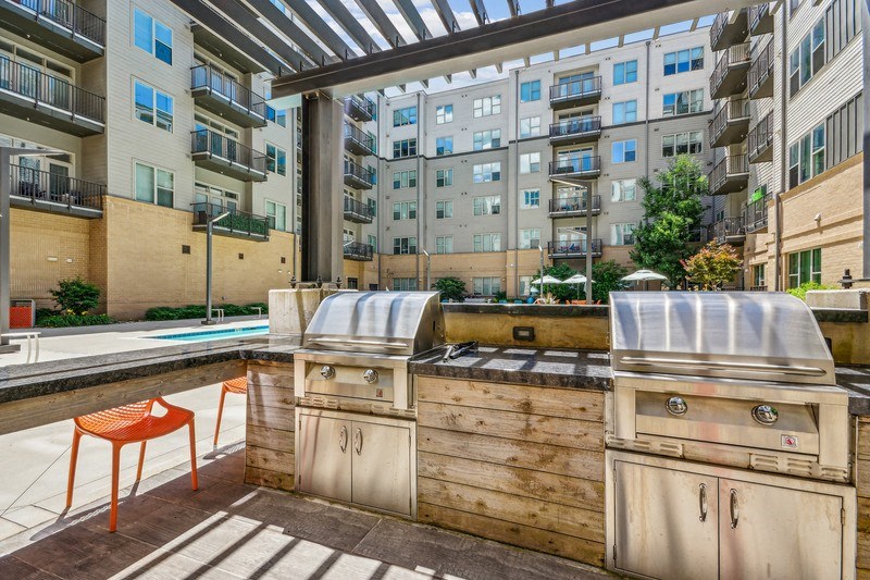 an outdoor kitchen with a grill and a pool in an apartment building at Link Apartments Innovation Quarter, Winston Salem, NC