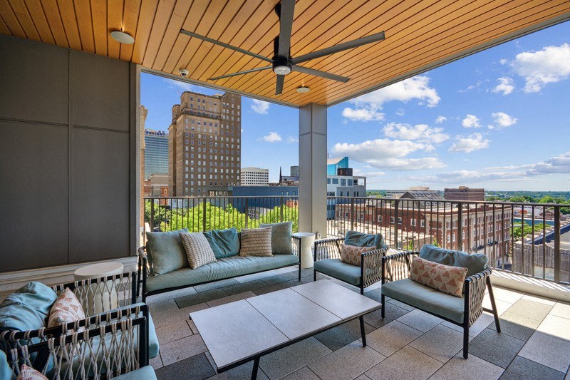 a balcony with a view of the city and a couch and a table at Link Apartments® 4th Street, North Carolina, 27101