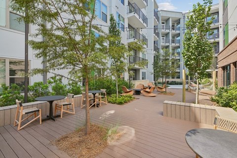 A wooden deck with a table and chairs is surrounded by trees.