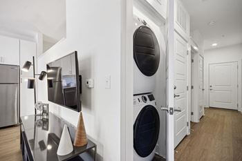 A modern kitchen with a washing machine built into the cabinetry. at Link Apartments® 4th Street, Winston-Salem, North Carolina