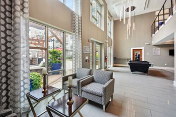 a lobby with chairs and a table in a building with large windows