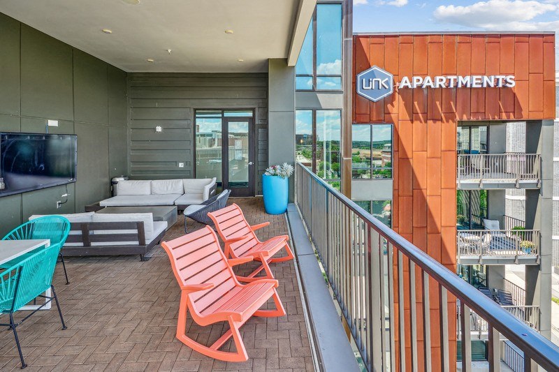a balcony with a couch and chairs and a television at Link Apartments Innovation Quarter, Winston Salem, NC, 27101