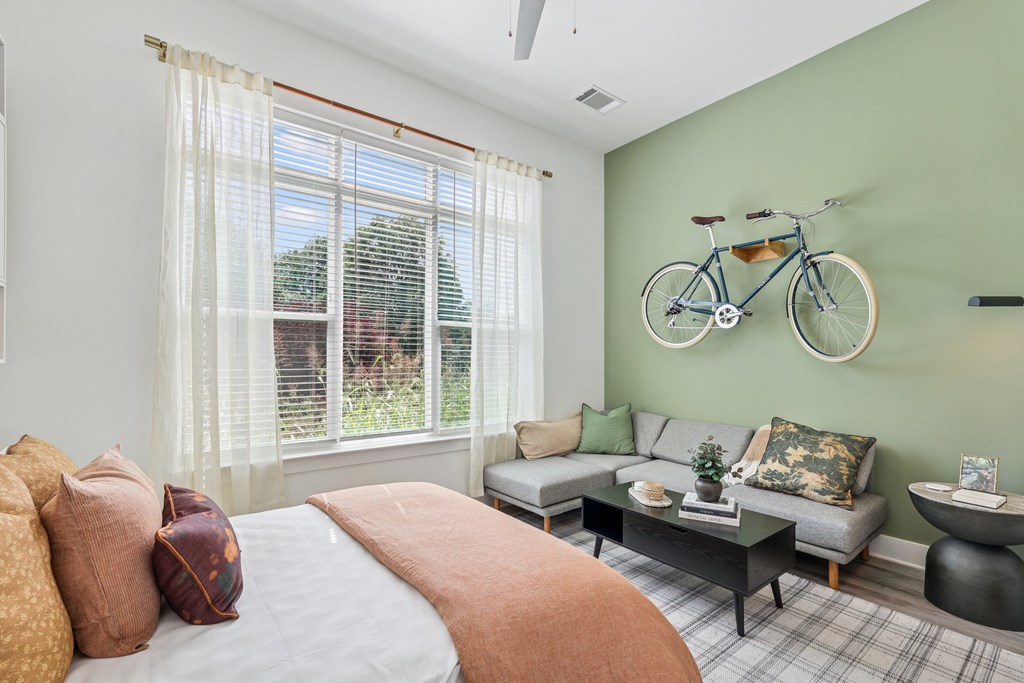 A bedroom with a bed, couch, and a bicycle on the wall at Link Apartments® CYKEL Apartments, Charlotte, NC