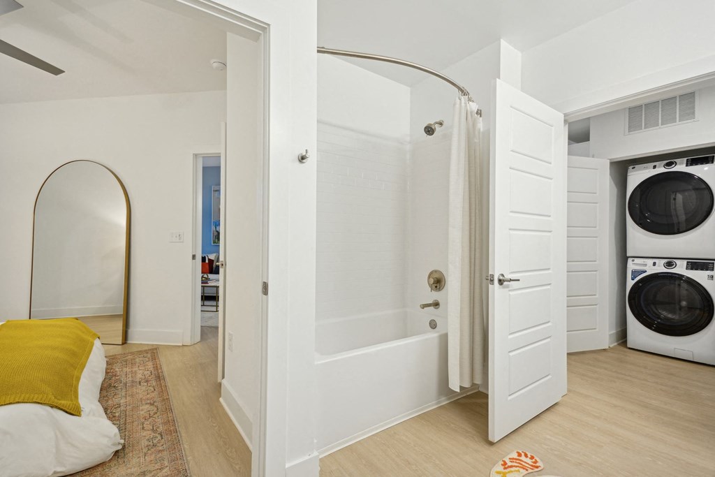 a bathroom with a washer and dryer and a door to a laundry room at Link Apartments® Calyx, Chapel Hill