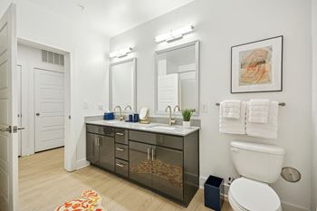 a bathroom with a sink and a toilet and a mirror at Link Apartments® Calyx, North Carolina, 27517