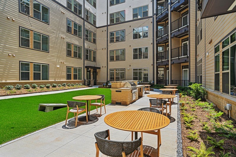 an outdoor patio with tables and chairs in front of an apartment building at Link Apartments® NoDa 36th, Charlotte