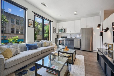 a living room with a couch and a coffee table in front of a kitchen at Link Apartments® 4th Street, Winston-Salem, 27101