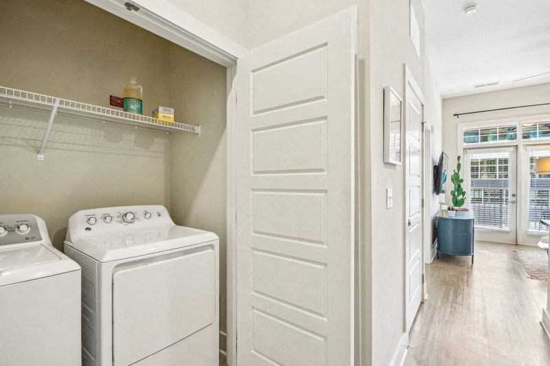 a laundry room with a washer and dryer and a white door at Link Apartments Innovation Quarter, Winston Salem