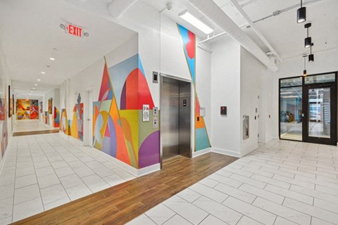a hallway with a colorful mural on the wall and a door at Link Apartments® 4th Street, Winston-Salem