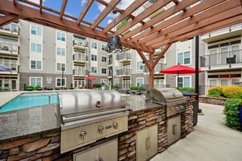 a patio with a grill and a pool with an apartment building