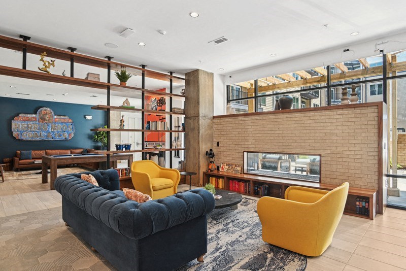 the living room of a condo with a blue couch and yellow chairs at Link Apartments® NoDa 36th, Charlotte, NC