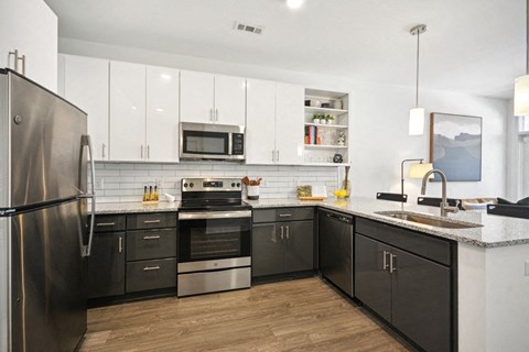 a modern kitchen with stainless steel appliances and white cabinets at Link Apartments® 4th Street, Winston-Salem, NC