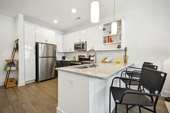 A kitchen with a white counter top and black chairs. at Link Apartments® 4th Street, Winston-Salem, North Carolina