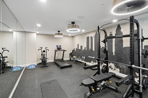 A gym with a variety of equipment including a treadmill, rowing machine, and weightlifting bench.